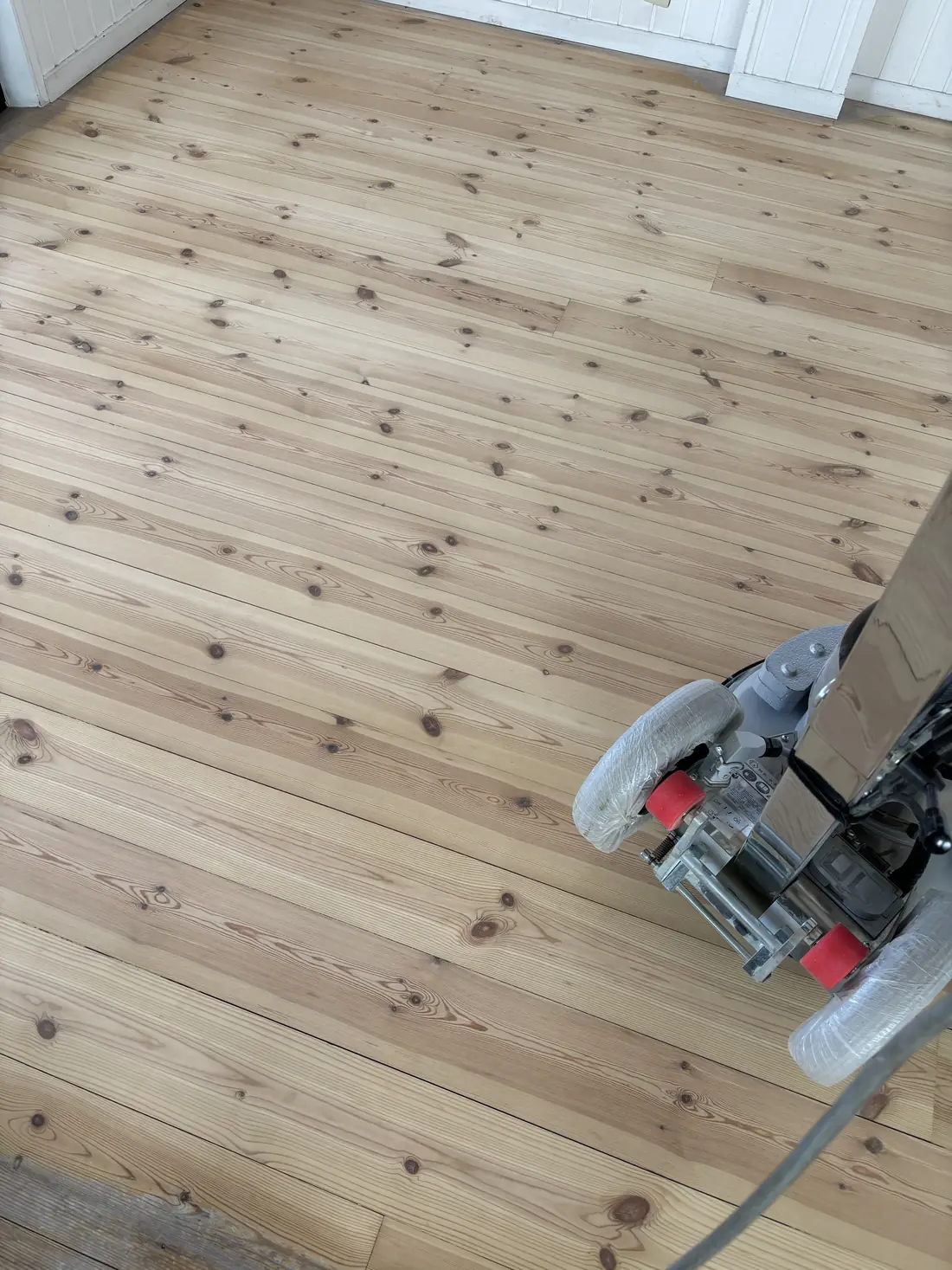 研磨がほぼ終わったパイン材の無垢フローリングと研磨機